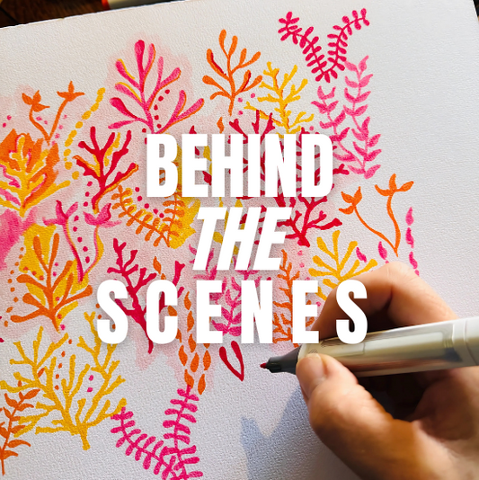 A close-up of a hand using a red marker to draw intricate coral patterns in shades of pink, orange, and yellow on paper, showcasing the detailed design process for West Indies Wear’s Caribbean-inspired collections. BEHIND THE SCENES.