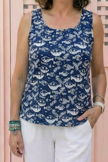 Person wearing a blue tank top with fish pattern against a pink background